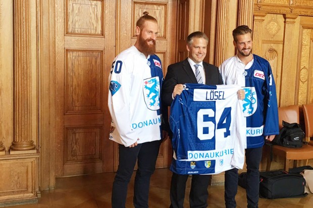 Thomas und Timo Pielmeier mit Oberbürgermeister Dr. Christian Lösel und dem neuen WarmUp-Trikot des ERC, das vorne das Ingolstadt-Wappen und hinten das Wappen der Landkreise zeigt...